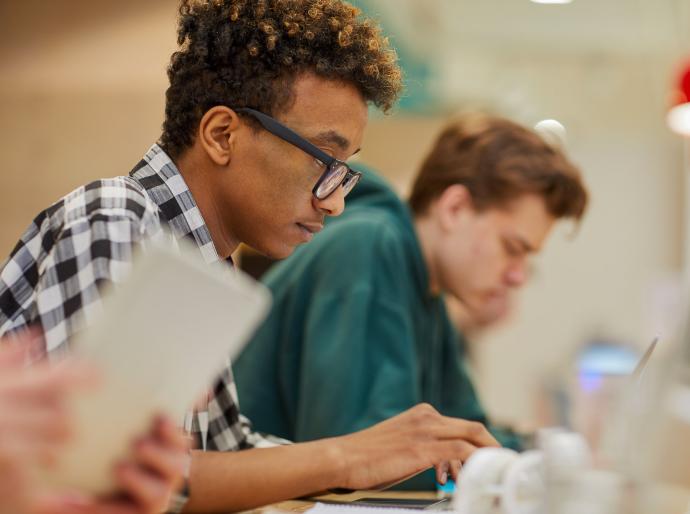 A focused student working on his laptop in a library