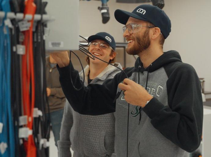 Two student in the electrical lab interacting while connecting wires in an electrical box