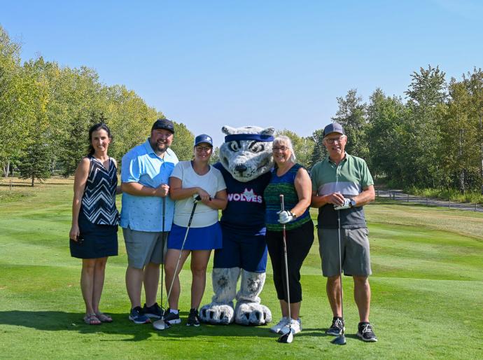 Golfers posing on the fairway with Farley the mascot at the 2025 Fairview Classic golf tournament