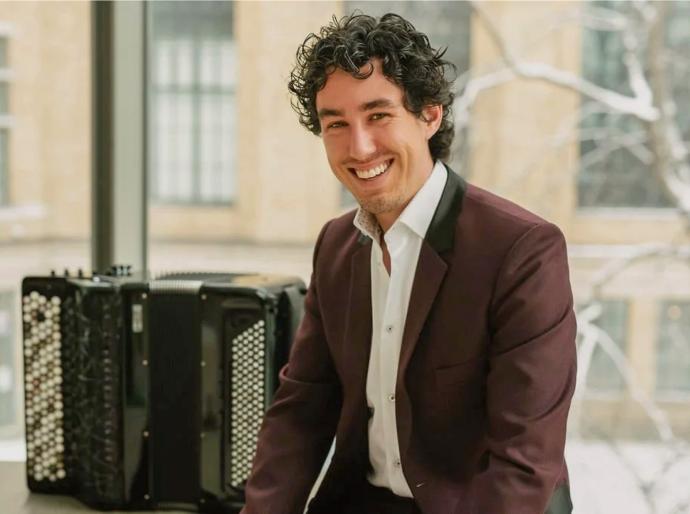 Musician Michael Bridge smiling in a pose beside his accordion