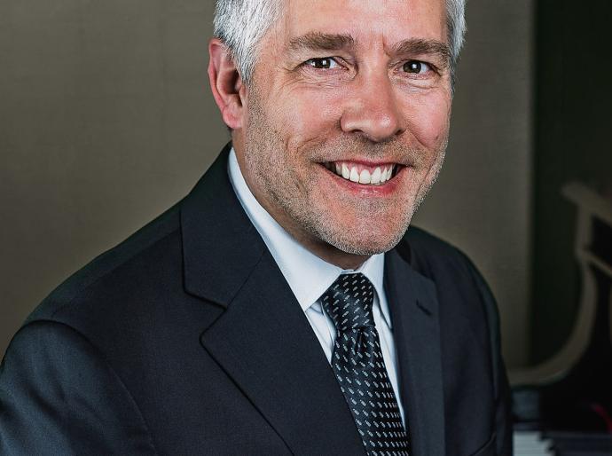 Headshot of a happy Roger Admiral sitting at his piano