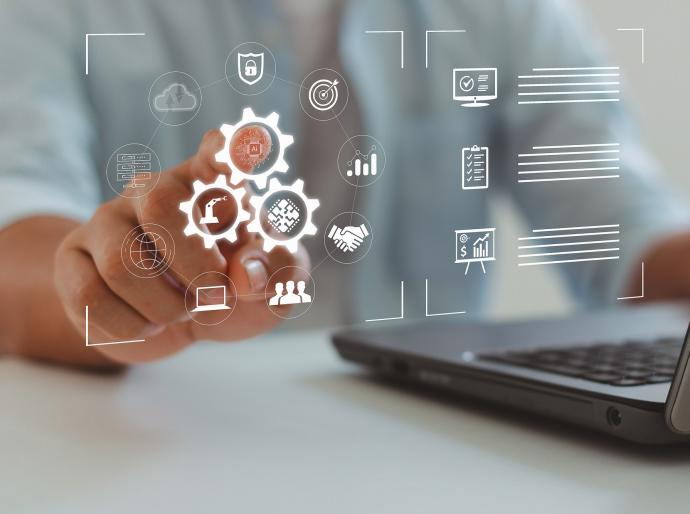 Person working on computer laptop with icons illustrating automation, industrial business process workflow optimization concepts on virtual screen.