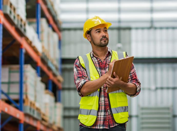 Warehouse manager holding a clipboard observing stock 