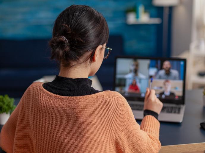 A student facing a laptop and engaging with people in an online meeting