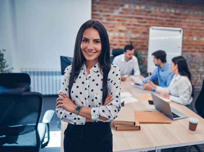 Office Professional standing in the boardroom with colleagues working in the background