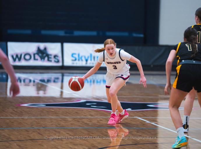Female basketball player dribbling the ball forward towards her opponent