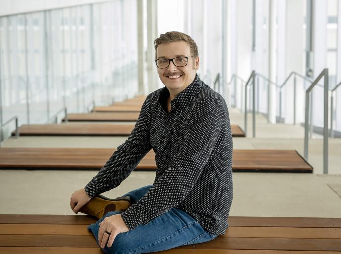Jason Bacon, Entrepreneur in Residence sitting on a bench in brightly lit assembly hall