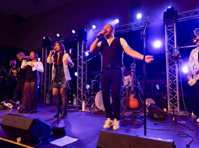 The lively band singinig enthusiastically on stage at the Presidents Ball