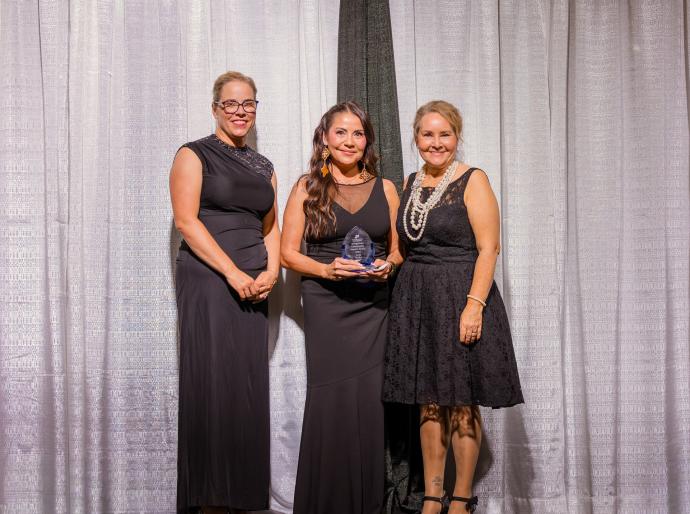 Lois Duke holds the Indigenous Impact Award onstage at the President’s Ball.