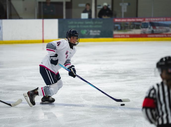 Wolves womens hockey player on the ice about to pass the puck