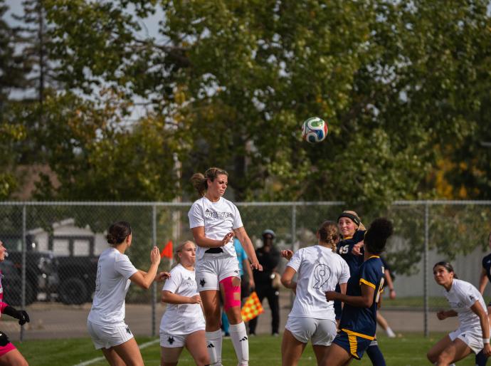 Wolves womens soccer player leaping high above the defense to connect with a powerful header.