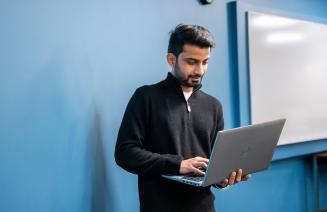 Student standing up using a laptop