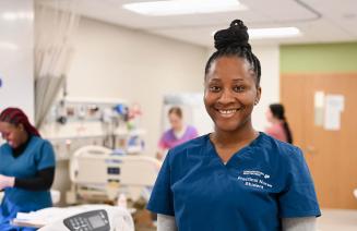 A happy practical nursing student standing in the simulation lab