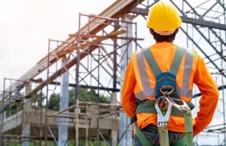 Worker wearing a hard hat and safety equipment on a job site.