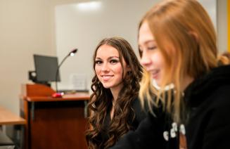 Happy student in classroom studying and smiling directly at the camera