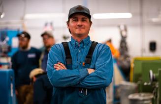 Happy trades person wearing coveralls standing in a workshop
