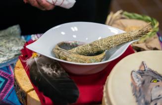 Close up of smudging stick, abalone shell, and turkey feather.