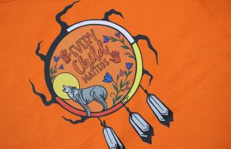 A close up of Every Child Matters artwork on an orange t-shirt