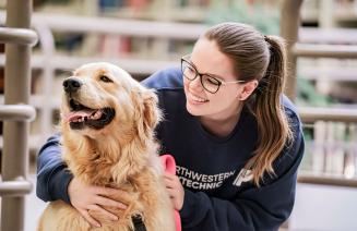 Student petting a therapy dog in the library on Grande Prairie Campus