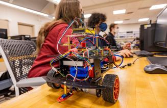 Students working on a robot with wheels in the robotics lab