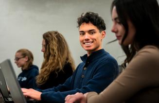 Happy student sitting in a computer lab smiling at the camera