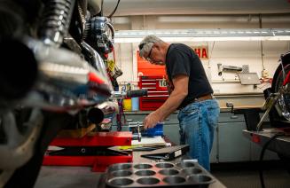 An NWP motorcycle mechanic instructor focused on repairing a motorcycle in a well-equipped workshop, surrounded by tools and parts