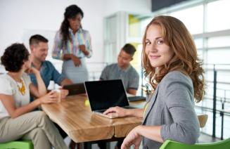 Smartly dressed woman sitting in a boardroom with professional colleagues.