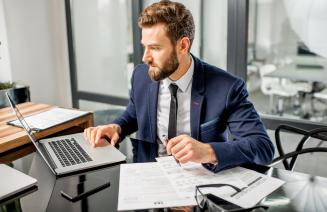 Smartly dressed businessman working at his laptop in a professional office.