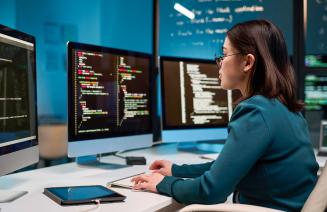 Computer programmer sitting at her desk focused on coding a program