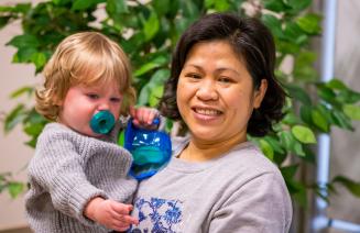 A happy early childhood educator comforting an infant.