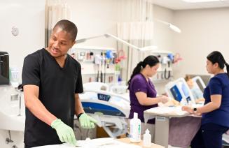 Group of nursing students with gloves on their hands and wearing scrubs working in the simulation lab