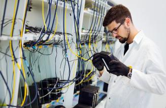 An IT support technician repairing a piece of hardware in the server room of a large company.
