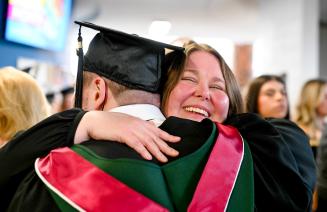 A graduate receiving a hug from a happy family member