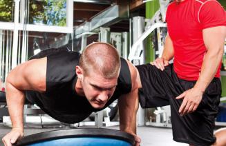 A fitness professional observing and guiding his client performing a push up