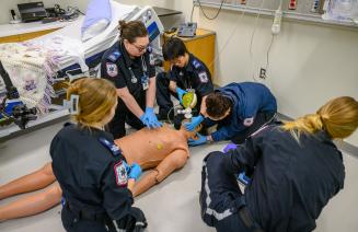Students in emergency services providing CPR to a dummy in the simulation lab