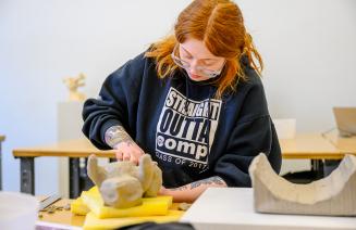 Fine arts student working on a sculpture of clay