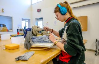 Arts student in the studio focused on creating a sculpture of a lion