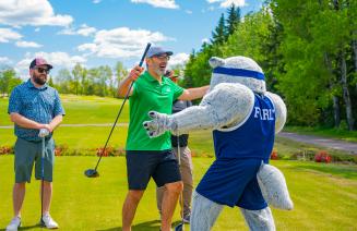 Farley the mascot shares an embrace with a happy golfer at the NWP classic