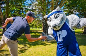 Farley the mascot sharing a handshake with a golfer at the NWP golf classic event.
