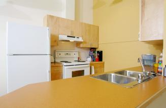 The inside of a housing unit at Fairview featuring a fridge, stove and counterspace