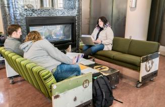 Three students sitting by the fireplace in Howlers lounge chatting and sharing notes