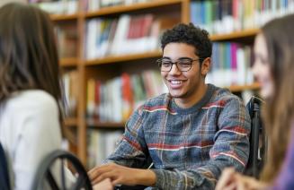Student in a wheelchair engaging with other students in a library