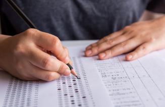 Close up of a student filling out and exam sheet with a pencil.