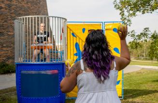 New student throwing a ball at a target on the dunk tank at orientation