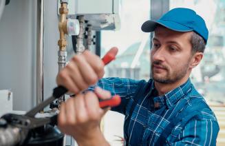 Pipefitter with a wrench performing maintenance on a piping system 