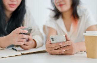 Close up of two women's' hands, holding mobile phones