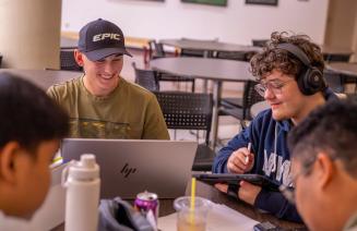 A group of happy students with laptops studying together