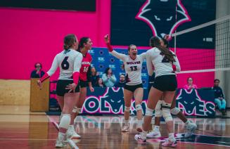 Womens wolves volleyball team celebrating on the court