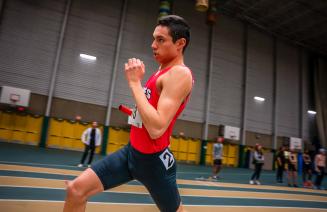 Wolves indoor track athlete sprinting in a relay