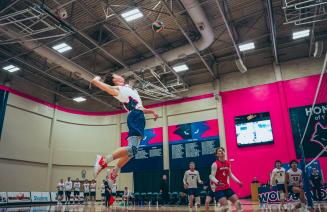 Wolves men's volleyball player floating in the air about to serve the ball